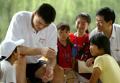 Chinese basketball star and Houston Rockets center Yao Ming (L) wipes tears for a Chinese AIDS orphan Zhang Yun during an HIV/AIDS awareness event at the Tsinghua University in Beijing July 17, 2005. Yao returned to China this week to take part in the NBA "Basketball without Borders" outreach event.